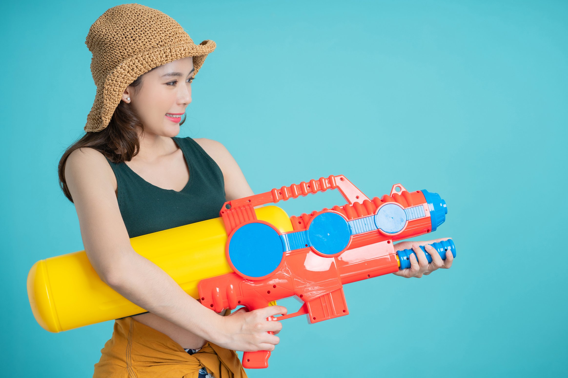 Beautiful woman holding water gun colorful on blue background, Songkran Festival.